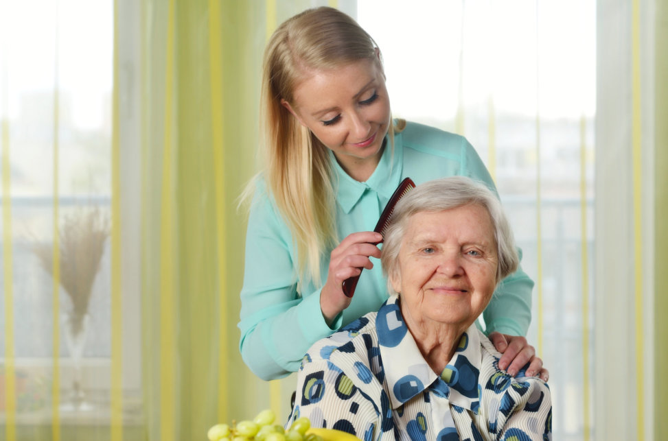 aide combing hair of elderly woman