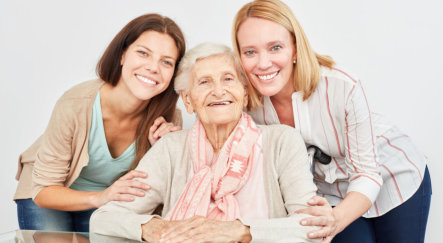 two ladies gathering around elderly woman